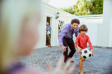 Father and son having fun with soccer ball in backyard