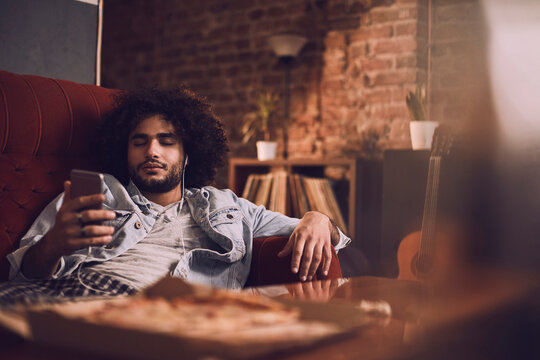 Carefree young man with eyes closed listening to music at home