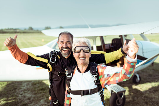 Portrait of happy senior woman and her instructor after skydiving