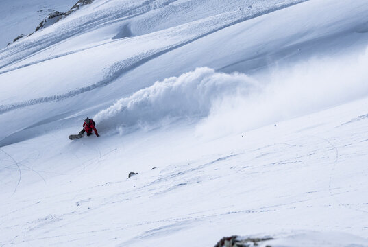 From above of Anonymous traveler with backpack snowboarding in Zermatt ski resort