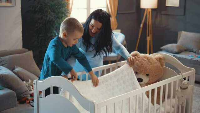 A three-year-old boy helps his pregnant mother by preparing togethers a cot for the baby they are expecting