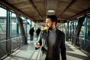 Professional young man in train station using smartphone