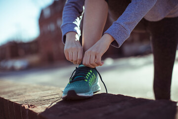 Woman tying running shoes for jog outside