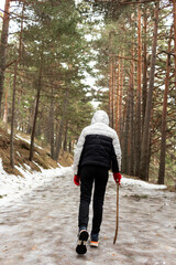 Teenage girl walking on a snowy trail surrounded by pine trees