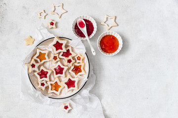 Traditional Linzer Christmas cookies filled with lingonberry jam and orange jam on wooden background	