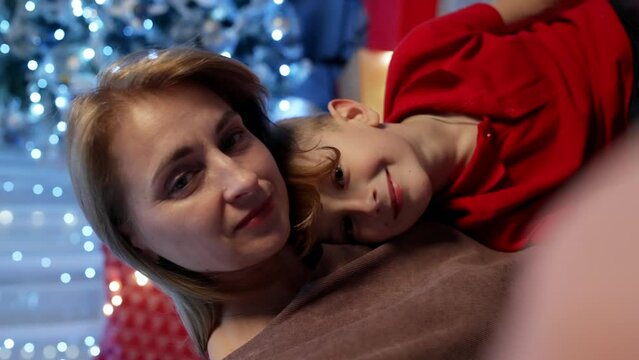 Mother and son take a selfie near the Christmas tree. Christmas memories phono for memory. Happy moments together, the love of parents for their children. High quality 4k footage