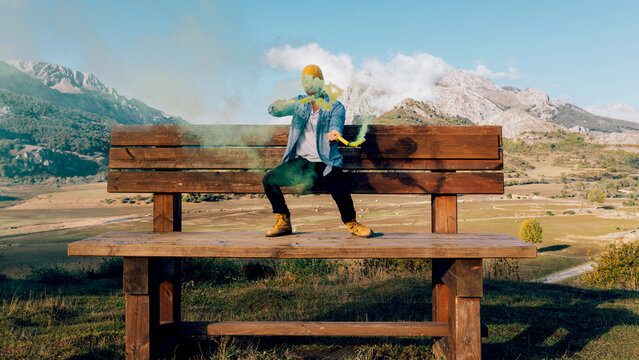 Creative person with colored smoke in a mountain landscape