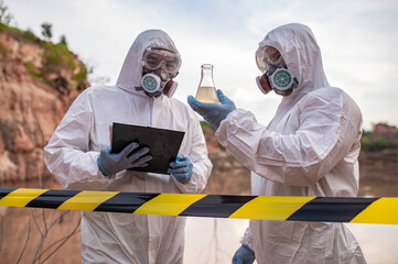 Scientists or biologists wearing protective uniforms working together on water...