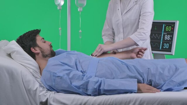 Man in bed with drip and heart rate monitor. Nurse draws in syringe and gives an injection into a man vein. Isolated on chroma key green screen.