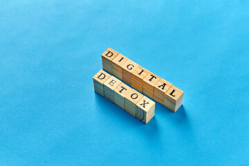 technology concept - digital detox words made of wooden toy blocks or stamps on blue background