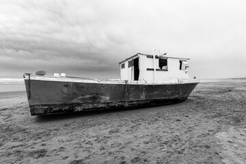 Abandoned deserted fishing boat stranded on a sandy beach on the central Oregon coast of the...