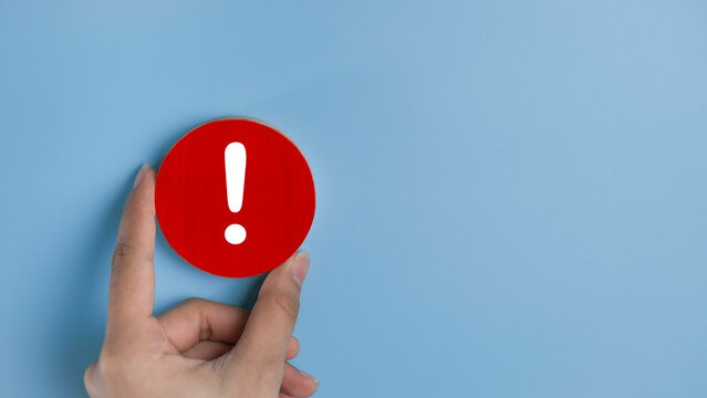 Attention caution warning concept. Hand holding red page with exclamation error mark for important alert signal, Hazard, risk ,danger background with copyspace.