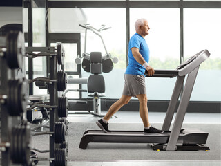 Mature man walking on a treadmill at the gym