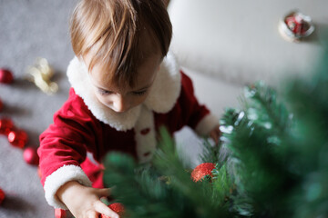 .Niño vestido de Papa Noel montando un árbol de navidad 