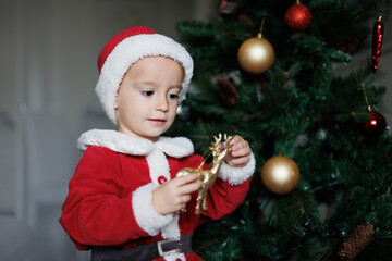 .Niño vestido de Papa Noel montando un árbol de navidad 