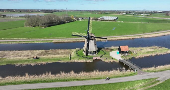aerial drone view of a Dutch historic windmill in the polder, specifically used for transportation and pumping of water.