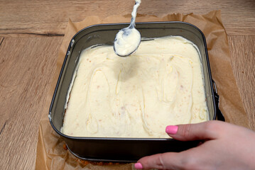 Preparation of Polish cake, fudge with custard cream, the woman applies the pudding mass.