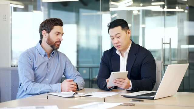 Business men discussing financial market data using laptop and digital tablet. Two diverse employees communicate Financial advisor broker manager consult investor client investment at office meeting