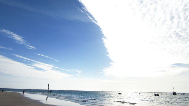 Praia com céu azul lindo e uma pequeno barco de fundo mais claro