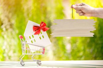 Man hand hold the label wood board with announce and offer for sale the house gift put in the...
