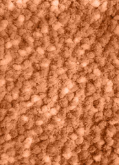 The background of fluffy material in the new trendy color of 2024 year Peach Fuzz. Texture top view. Blog backdrop for text signs design. Abstract wallpaper, textile surface.