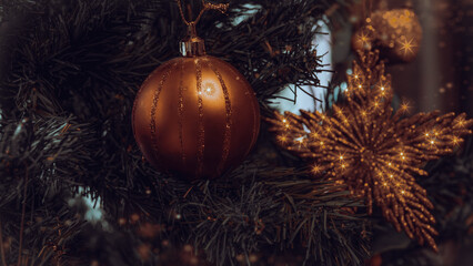 Christmas tree decorated with golden colored ball and gold tinsel star and apple on blurred...