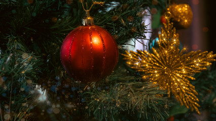 Fototapeta na wymiar Christmas tree decorated with red ball and gold tinsel star and apple on blurred background
