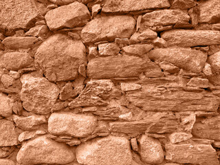 Old stone wall colored in new trendy color of 2024 year Peach Fuzz. Stone texture. Horizontal background. Copy space