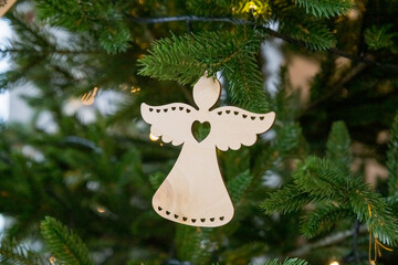 Handmade Christmas angel hangs on a branch of a Christmas tree with balls and wooden toys. Christmas zero-waste ornaments. wooden eco toys. New year decor.