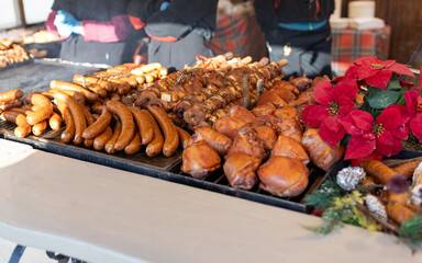 Grilled sausages in street market in a medieval fair in Poland. Sausages and pork ready to eat. Festival of street food and meat. Selling traditional hot food at the Christmas Fair