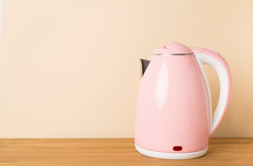 Pink electric kettle on wooden table