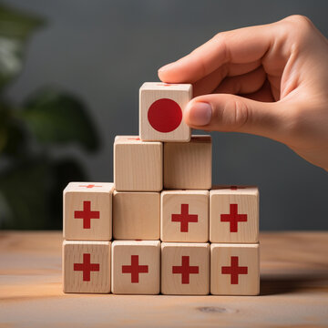 Hand stacking wooden blocks with red and white symbols. Conceptual image of business success.