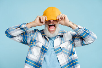 Funny bearded man wearing stylish yellow hat and shirt, standing isolated on blue background