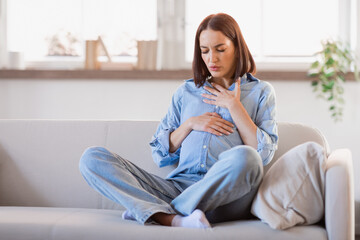 Pregnant lady feeling bad touching tummy and chest at home