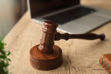Closeup wooden gavel hammer with laptop on desk in law firm or lawyer office background as justice...