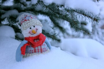 beautiful homemade sewn plush snowman hstay near  Christmas tree on the street. The snowman has a...