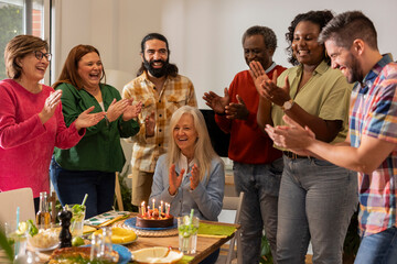 Multi-generation family celebrating grandmother's birthday at the table with food and cake at home