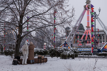 Kyiv, Ukraine - December 12, 2023: in the evening in frosty weather, families and friends gather at VDNG, where a New Year's fair was opened. they go for a walk, drink hot coffee, and ride rides.