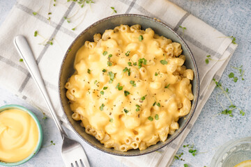 Bowl of tasty Italian pasta with Cheddar cheese on light background