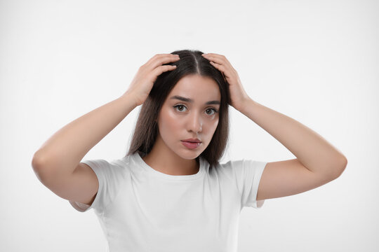 Woman suffering from dandruff problem on white background