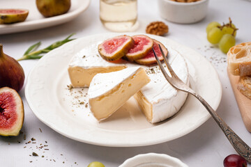 Plate with pieces of tasty Camembert cheese on grey background