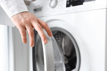 Young man opening washing machine, closeup