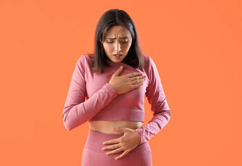 Beautiful young afraid woman on orange background