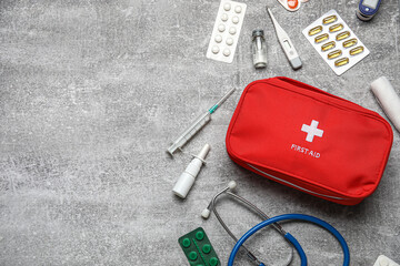 First aid kit and pills on grunge grey background