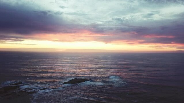 Drone, ocean and sunset with rocks, nature and clouds with horizon, seascape and waves in environment. Water, sea or lake with sky background with ecology, sustainability and beach with stone at dusk