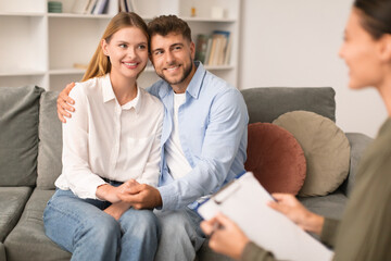 Loving husband and wife embracing sitting together in psychotherapist's office