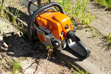 Fototapeta premium an orange chainsaw on the territory of a country house, used for sawing firewood