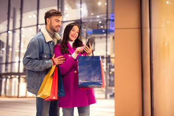 Couple doing online shopping on phone on evening near mall