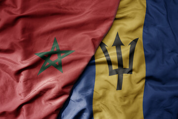 big waving national colorful flag of barbados and national flag of morocco .