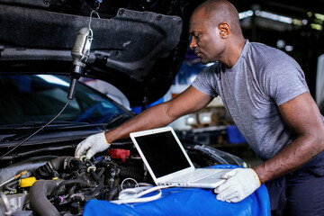 Mechanic using compute for Diagnostic  machine tools ready to be used with car. Car mechanic using a computer laptop to diagnosing and check up on car engines parts for fixing and repair - obrazy, fototapety, plakaty